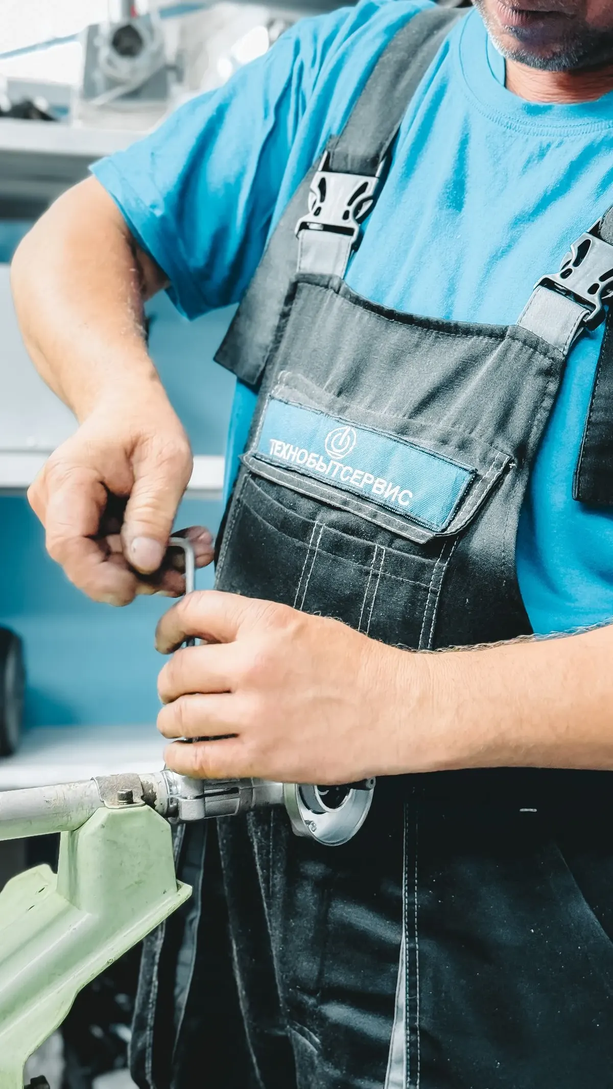 Plumber in overalls repairing a water heater pipe fitting with a wrench
