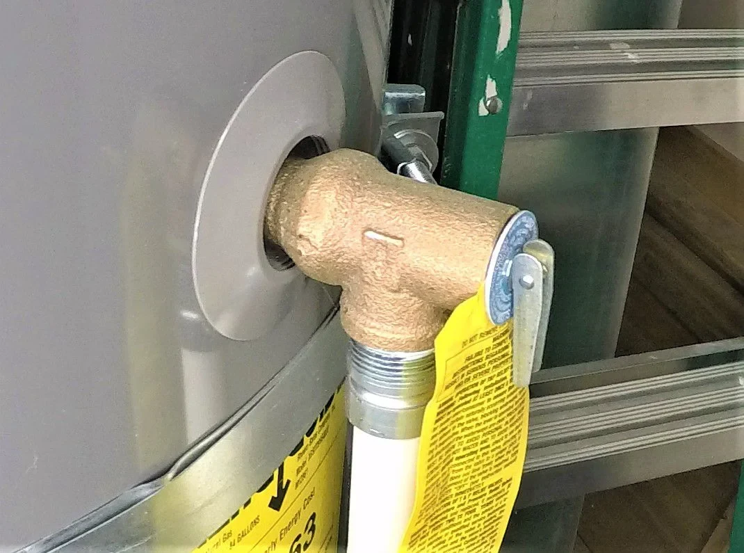 Brass pressure relief valve fitted on the side of a water heater tank